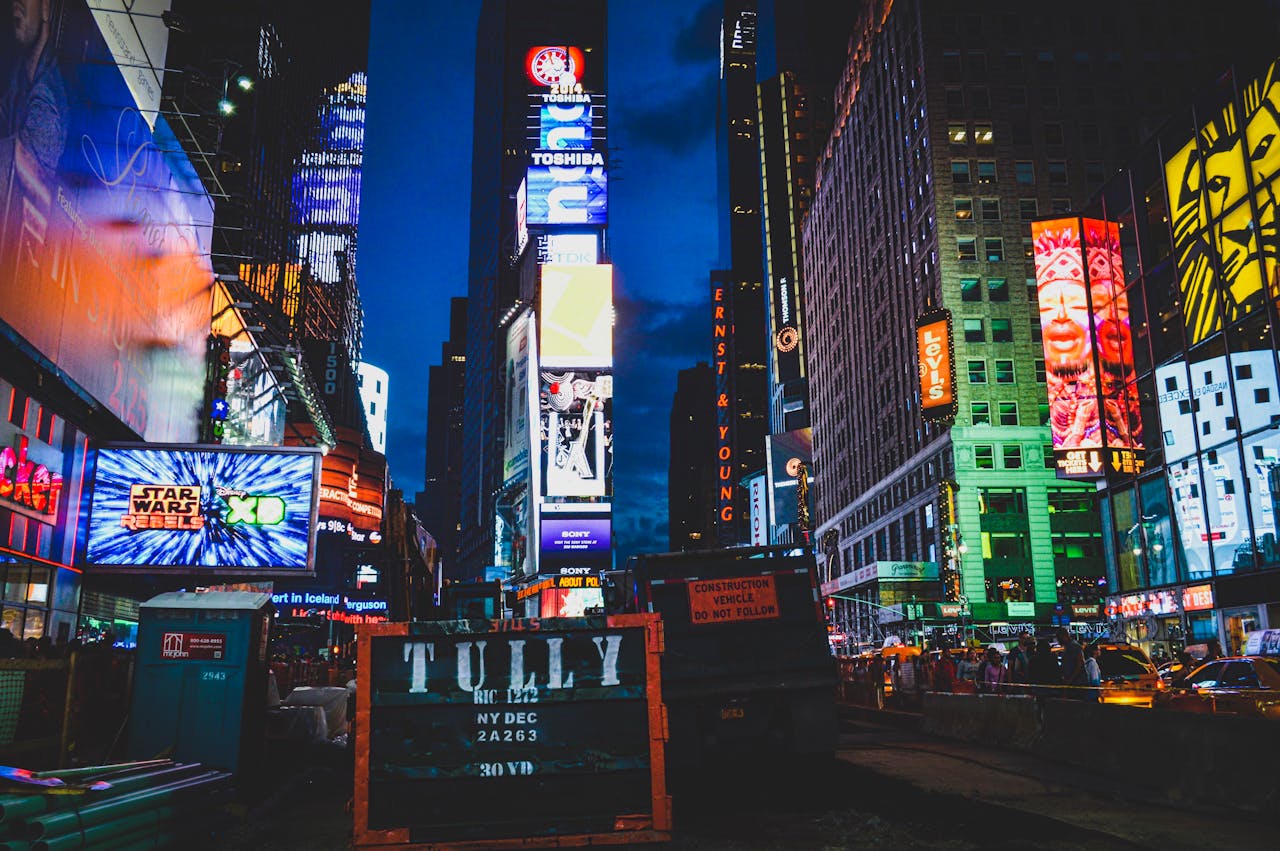 about-01 An iconic view of Times Square, New York City, illuminated with colorful lights and billboards at night.